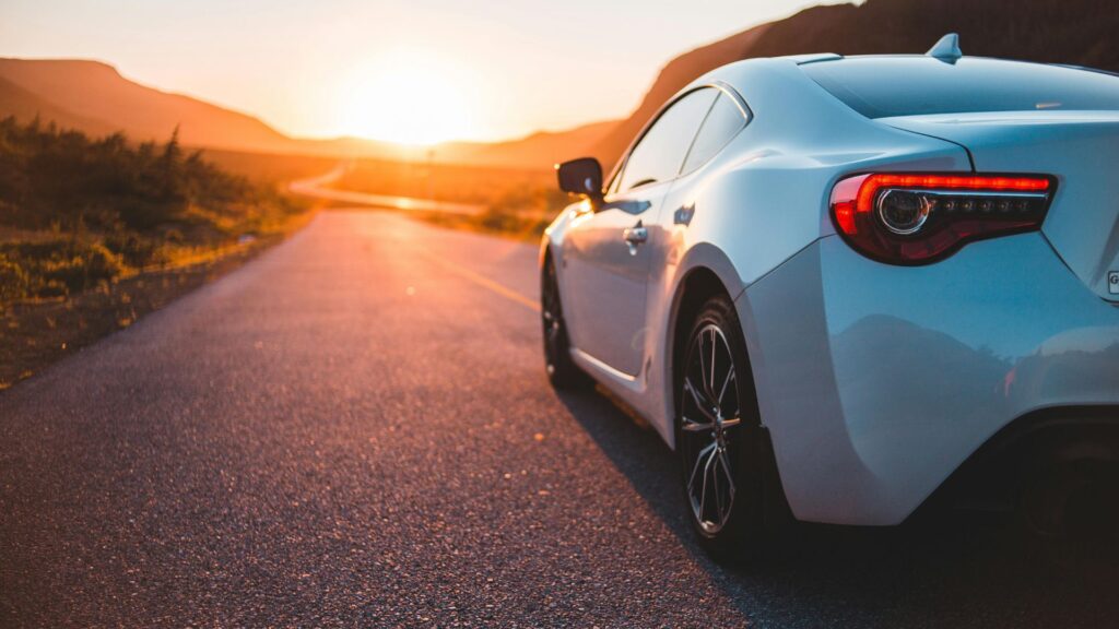 夕暮れの道を走る白い車